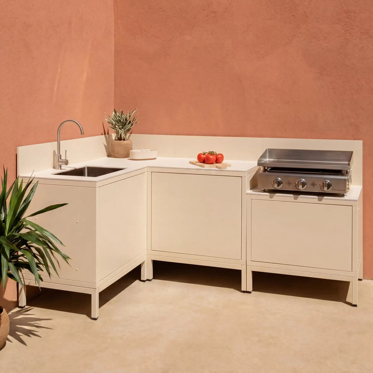 Cuisine extérieure d'angle Pilotis blanc crème avec plan de travail en céramique blanc, évier et plancha Vivaplancha.
::visuel:creme