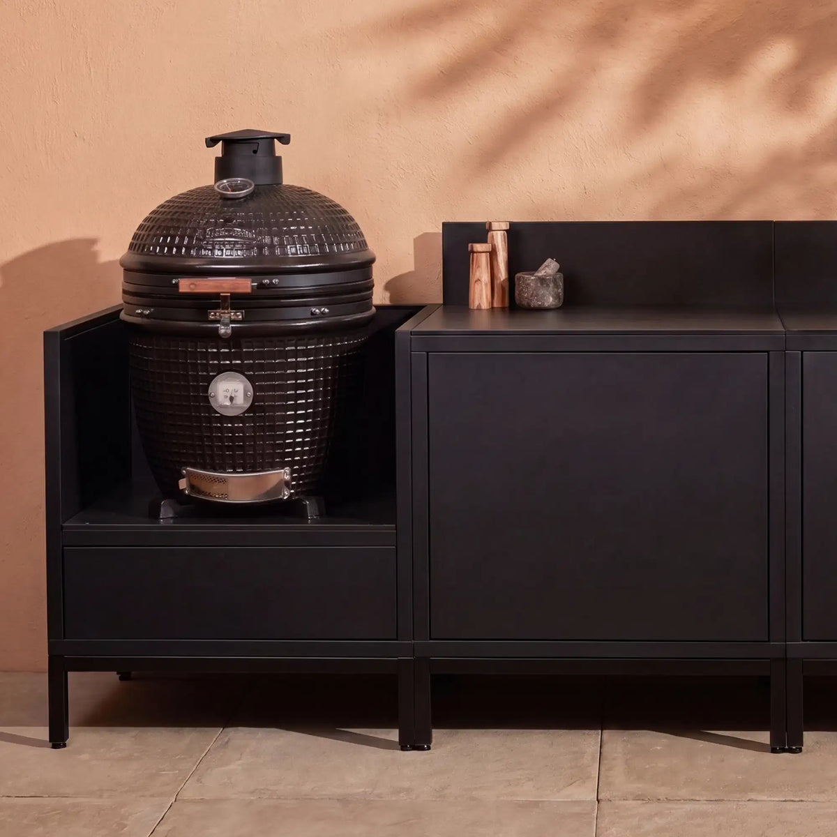 Cuisine extérieure Pilotis noir profond avec module kamado et plan de travail en céramique noir.
::visuel:noir