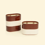 Bougies Totem S Rouge oxyde – Citronnelle & Géranium et Beige ivoire – Citronnelle & Citron, deux bougies ovales à double mèche en bois, posées sur un fond beige clair. ::visuel:geranium
