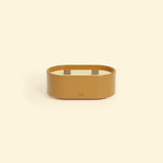 Bougie Totem S Brun terre de sienne – Citronnelle & Fleur d’oranger, bougie ovale à double mèche en bois, posée sur un fond beige clair.::visuel:fleur