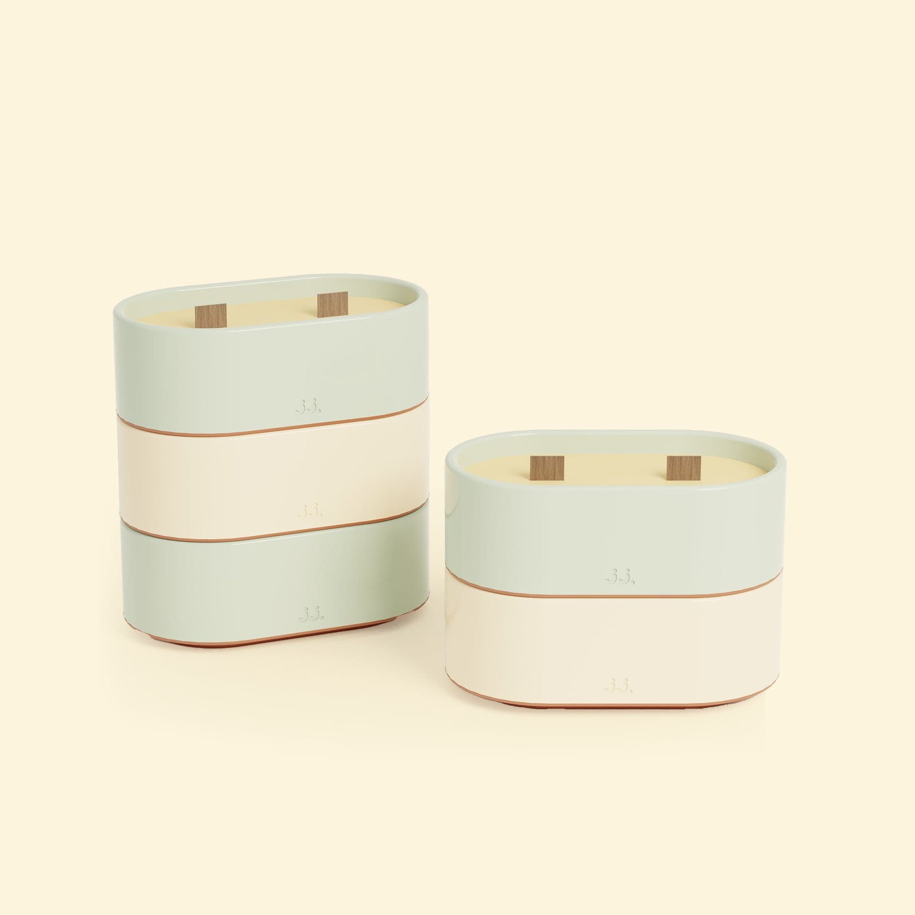 Bougies Totem S Vert d’eau – Citronnelle & Eucalyptus et Beige ivoire – Citronnelle & Citron, deux bougies ovales à double mèche en bois, posées sur un fond beige clair. ::visuel:citron