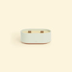 Bougie Totem S Vert d’eau – Citronnelle & Eucalyptus, bougie ovale à double mèche en bois, posée sur un fond beige clair. ::visuel:eucalyptus