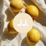 Citron jaune sur tissu clair avec logo jj., évoquant la senteur Citronnelle & Citron. ::visuel:citron