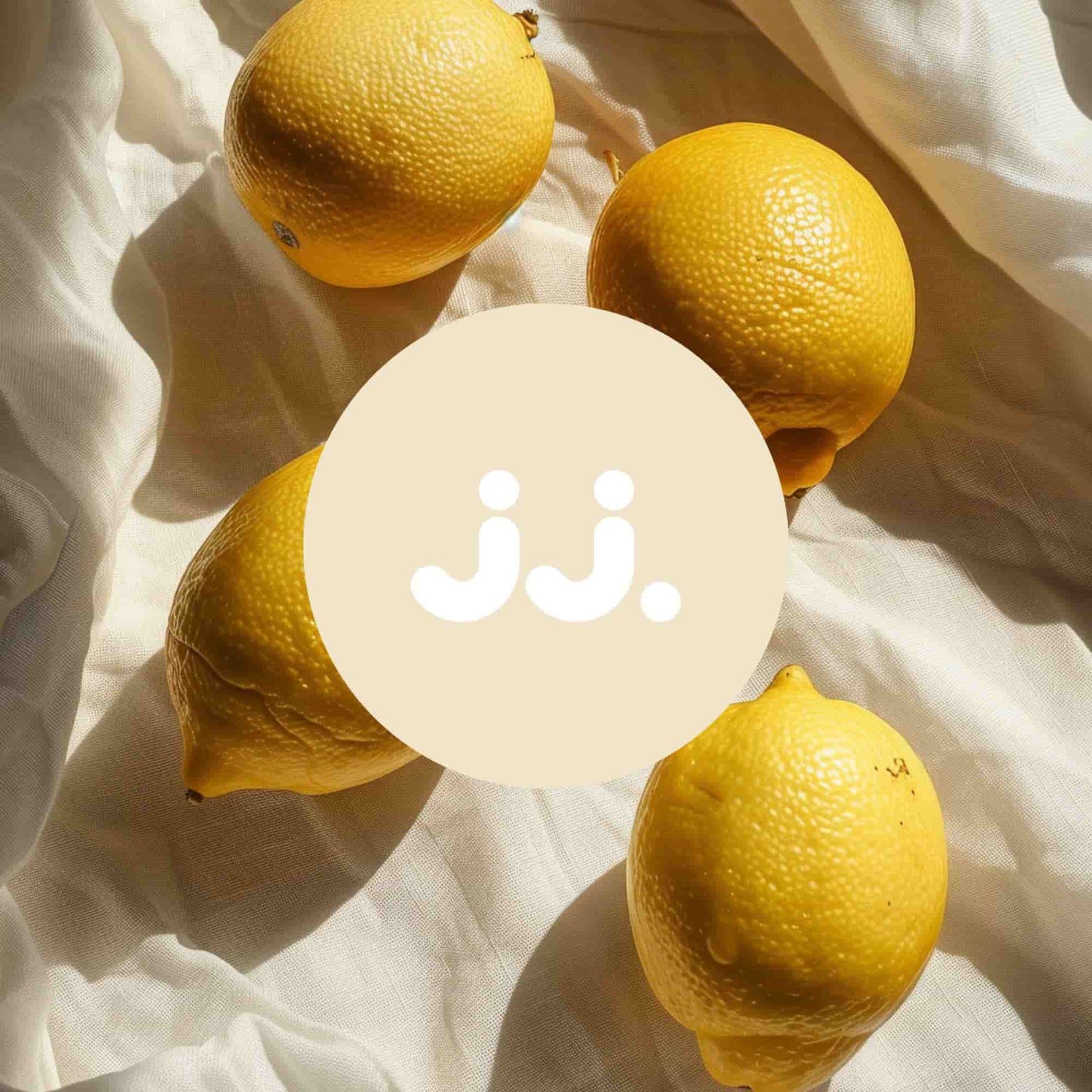 Citron jaune sur tissu clair avec logo jj., évoquant la senteur Citronnelle & Citron. ::visuel:citron
