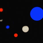 Guirlande lumineuse tricolore floue en situation nocturne, avec des points lumineux bleu, blanc et rouge ressortant sur un fond sombre pour une ambiance festive.