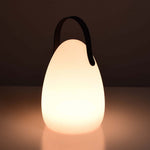 Lampe solaire d’extérieur en forme d’œuf, allumée et diffusant une lumière chaude et apaisante, avec anse noire arrondie.