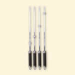 Lot de quatre brochettes longues en inox avec manche noir et bagues réglables, alignées sur fond beige.
