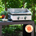 Plancha Vivaplancha en inox posée sur un chariot extérieur, accompagnée de légumes frais, avec un badge “Structure tout inox” en bas à droite.